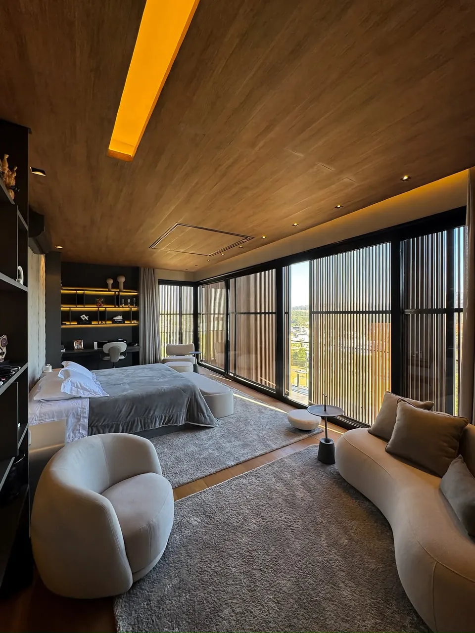 Quarto com área de estar e brises de madeira