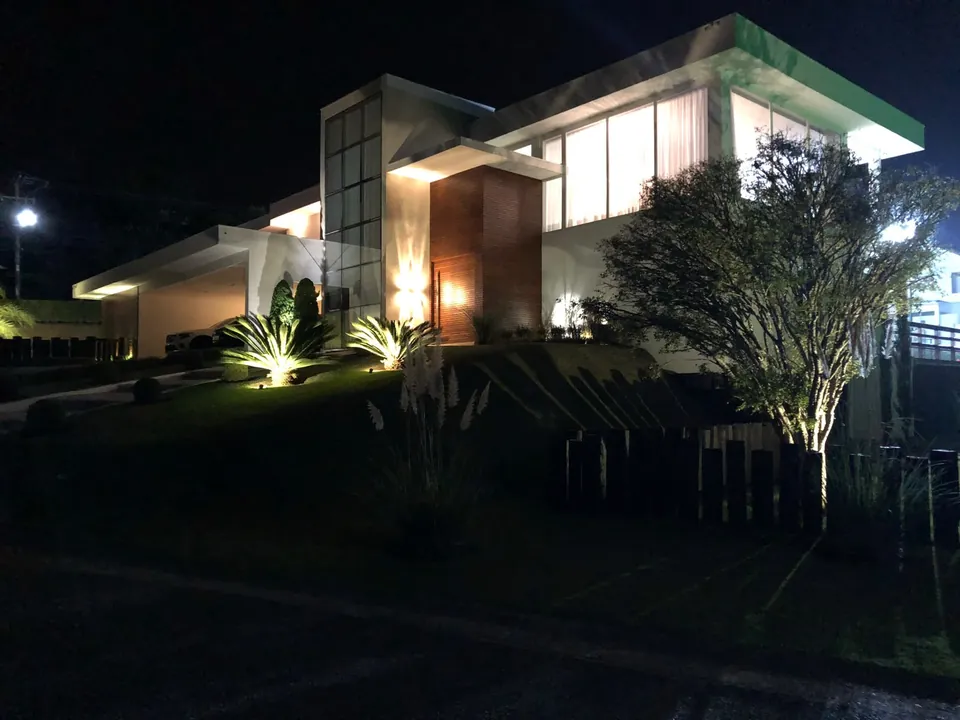 Fachada noturna com jardim iluminado